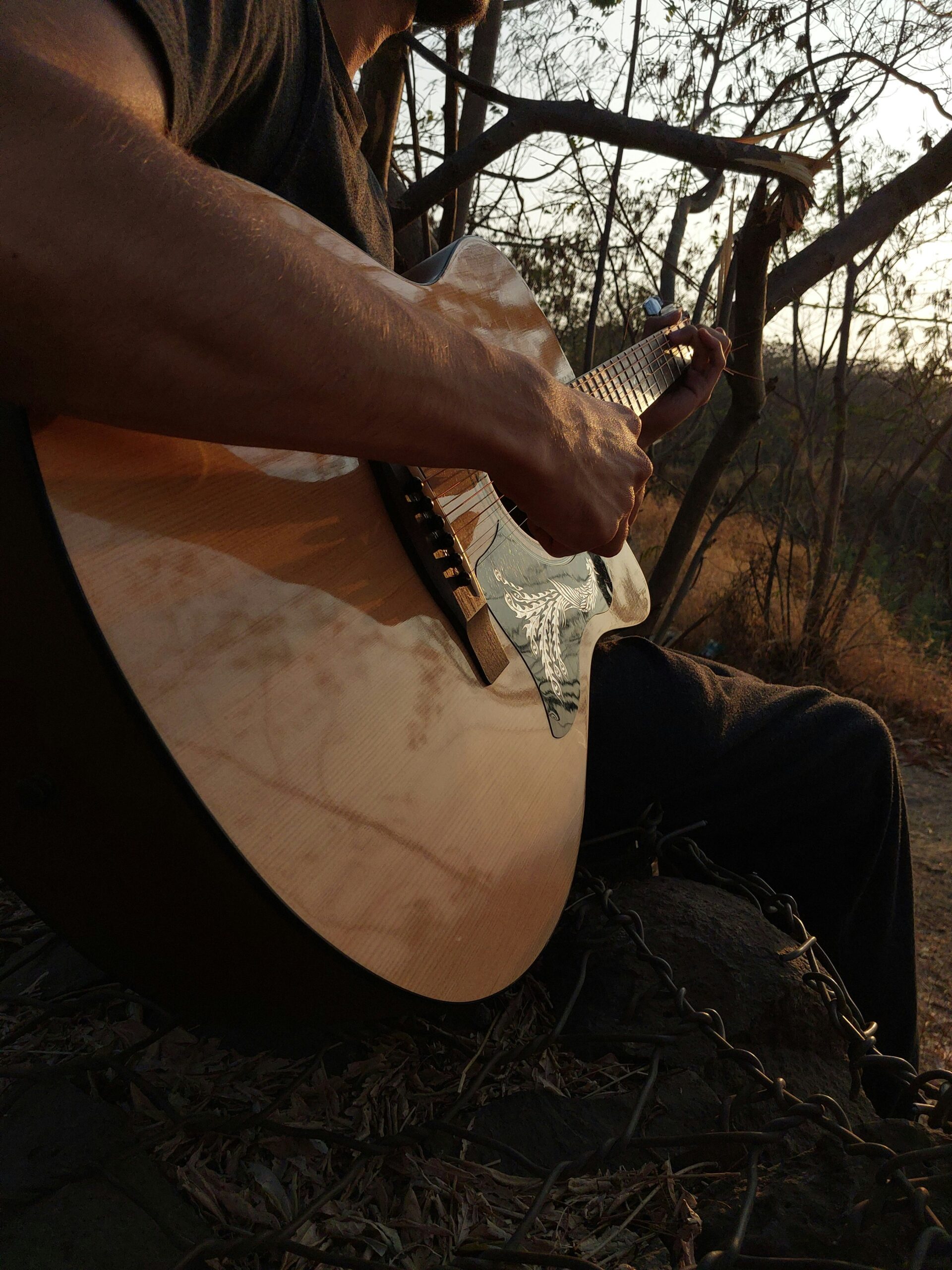 a man sitting on the ground playing a guitar